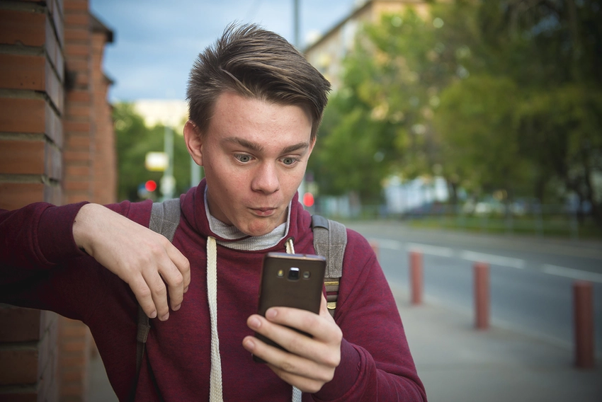 slideshow can be bad news. Teen boy reads sms on smartphone